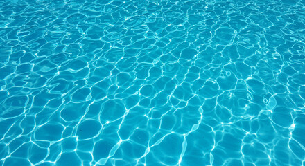 Sunlight creating bright ripple patterns on the surface of clear blue swimming pool water in a relaxing summer scene.