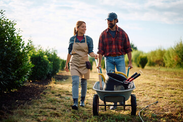 Happy couple of farm workers walking through plant nursery.