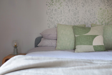 a queen bed made up with green cushions