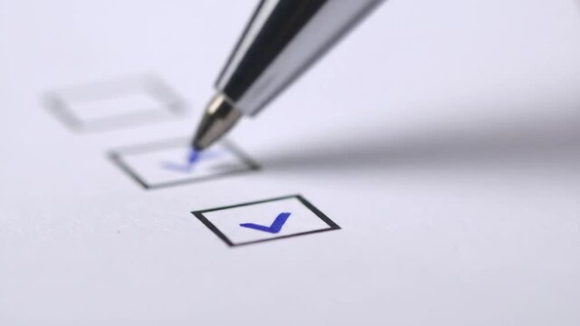 Close-up of a pen marking checkboxes on a form.