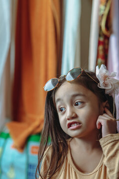 Little girl with sunglasses and flower on her hair is talking.