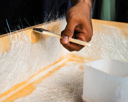 Brushing fiberglass sheets on a wooden box. A diy project at home.
