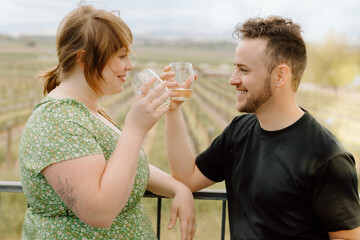 Couple toasts with wine glasses at scenic vineyard