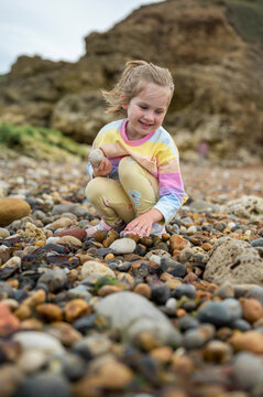 Family holiday at seaside. Little girl picking stones at the beach