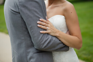 Bride embraces groom&rsquo;s arm, highlighting wedding ring and love