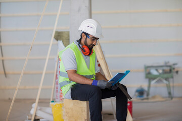 worker with helmet and safety jacket checking a tablet