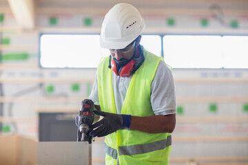 worker with helmet and safety jacket working in wooden hall