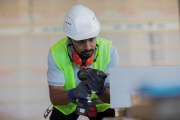 worker with helmet and safety jacket working in wooden hall