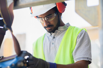 worker with helmet and safety jacket working in a wooden hall