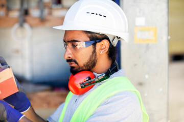 worker with helmet and safety jacket working in a wooden hall