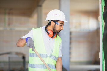 worker with helmet and safety jacket working in a wooden hall