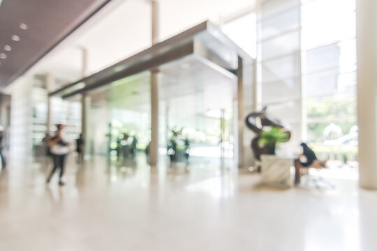 Hotel or office building lobby blur background interior view toward reception hall, modern luxury white room space with blurry corridor and building glass wall window