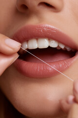 Person using dental floss for oral hygiene in a close-up shot, emphasizing the importance of daily teeth cleaning and self-care routines for maintaining health and freshness