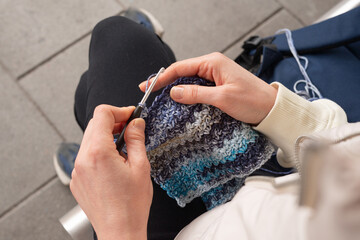 Caucasian adult female crocheting with blue yarn outdoors in casual attire I Love Yarn Day