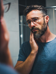 Trimming beard in front of a modern mirror during a morning self-care routine for maintaining hygiene and looking fresh
