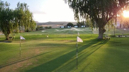 Golf course practice area at sunset. Range practice area golf club. Green, flags and golf holes. practice facility golf area. Granada. Spain. - Powered by Adobe