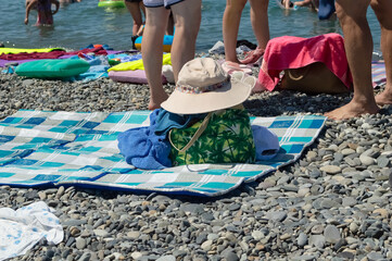 on a pebble beach by the sea there are things, a towel, a hat against the background of the sea