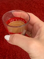 Woman holding a cup of espresso coffee against a red background 