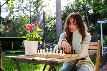 Father and tween daughter playing chess in their backyard on a summer day. Quality family time and mental development in a relaxed outdoor setting.