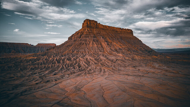 Iconic lone desert mesa rising from deeply etched land patterns