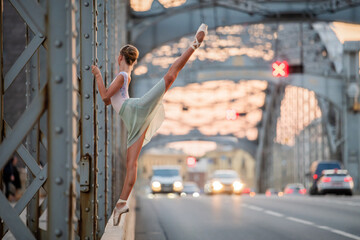 ballerina performing elegant ballet pose on a bridge at sunset