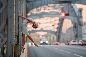 ballerina performing elegant ballet pose on a bridge at sunset