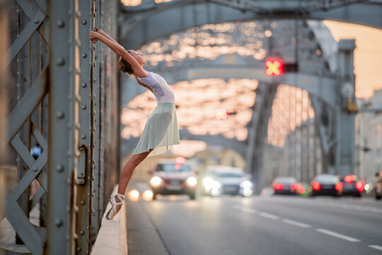 Fototapeta ballerina performing elegant ballet pose on a bridge at sunset