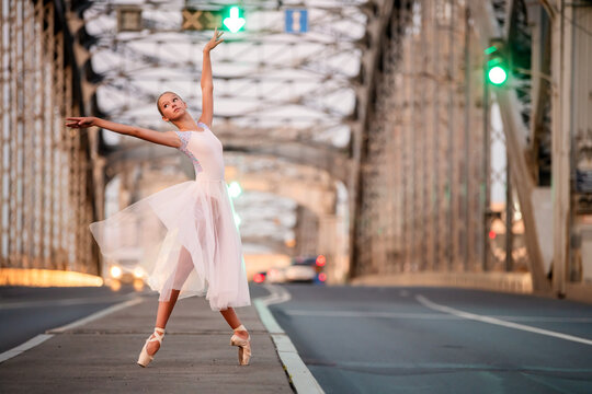 Young ballet student girl dancing on city bridge
