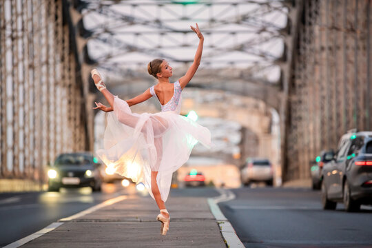 Young ballet student girl dancing on city bridge
