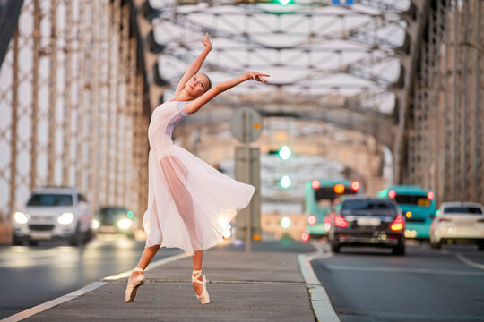 Young ballet student girl dancing on city bridge