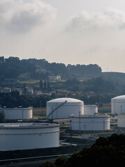 Fototapeta premium Large white oil storage tanks in rural industrial landscape