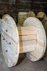 Large empty wooden cable drum in industrial warehouse. Untreated wood reel for fiber optic or wire...