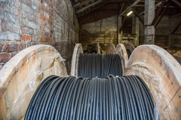 Large black electric cable spools stored in an old industrial warehouse. Power line wiring for...