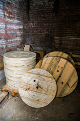 Stack of wooden cable reels in a dark, old storage room or warehouse, industrial background. For...