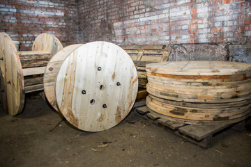 Empty wooden cable reel drums abandoned in an old warehouse, awaiting reuse or recycling for...