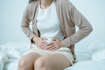 Women who are experiencing stomach pain in bed, stomach pain from food poisoning, stomach pain and...