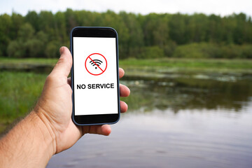 Hand holding smartphone with no service in nature reserve