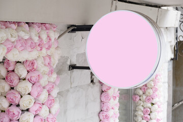 Mockup of a blank round lightbox shop sign with a pink surface, mounted on a white brick wall...