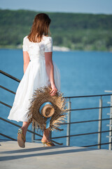 Woman with brown long hair in summer dress walking near a lake