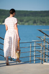 Woman with brown long hair in summer dress walking near a lake