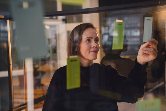 Businesswoman planning strategy in modern loft office with glass board