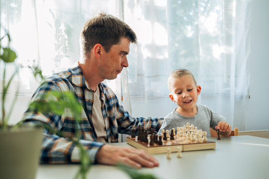 Father and son playing chess together at home enjoying family time