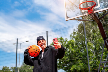 Stylish female taking photo with phone on urban basketball court
