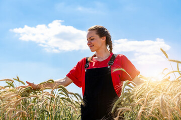 Smiling woman walking through grain field and touching crops