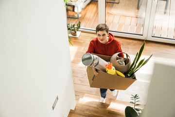 Woman carrying box while moving and cleaning up at home happily