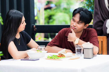 Southeast Asian couple exchange differing opinions, with the man thinking hard during a...