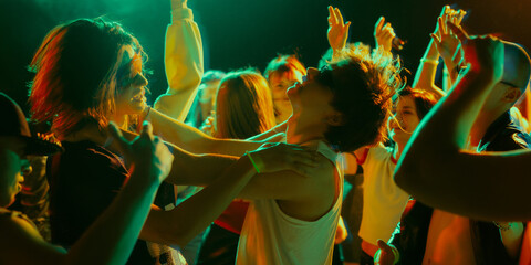 Energetic crowd dancing at a lively party with colorful lighting and upbeat atmosphere. Concept of...