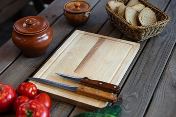 Top-down view, variety of fresh tomatoes and cucumbers next to a wooden cutting board with two...