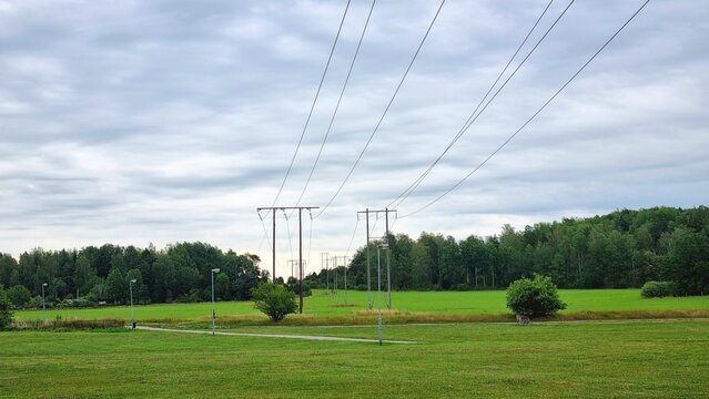 power lines on a field. energe comunicative on the street, sky. Tall lattice steel transmission tower carrying multiple power lines stands against a blue sky - Powered by Adobe