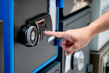 Hand try to press button on modern keypad lock on safe at home decor store. Customer choosing...